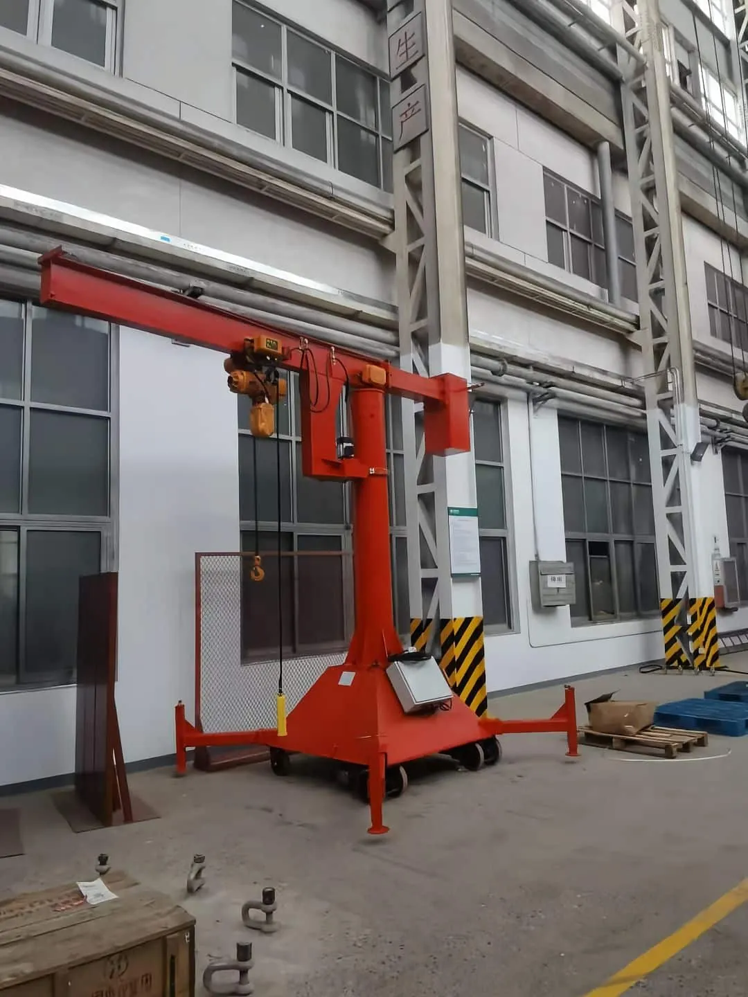 Mobile jib crane with chain hoist beside a workshop