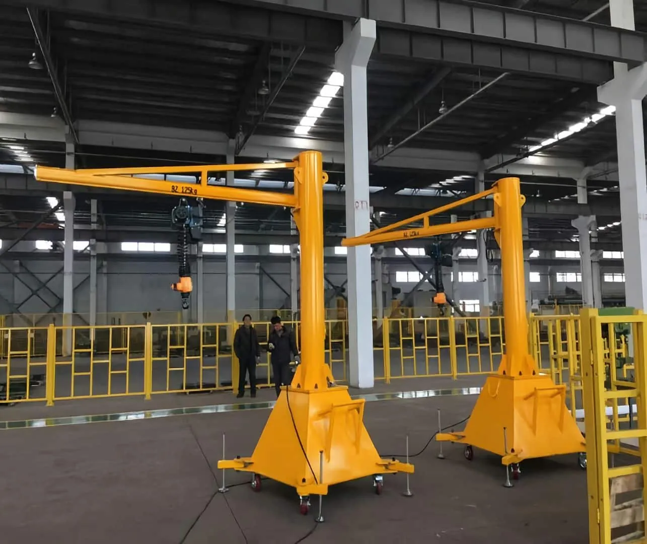 Kitanocrane mobile jib cranes with wheeled bases in a factory workshop