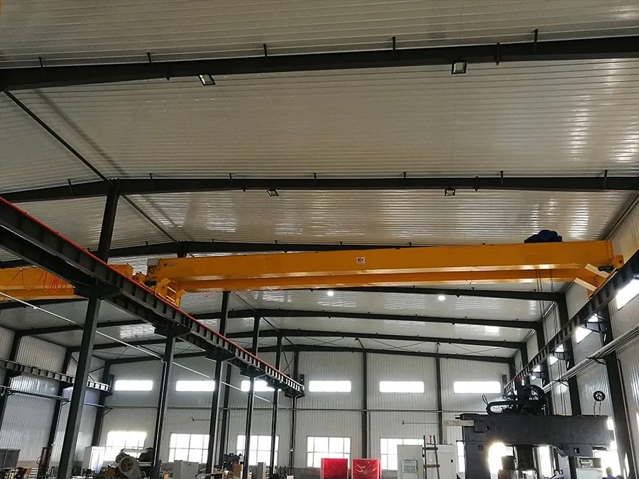 Heavy-duty double-girder overhead crane working in steel fabrication industrial workshop