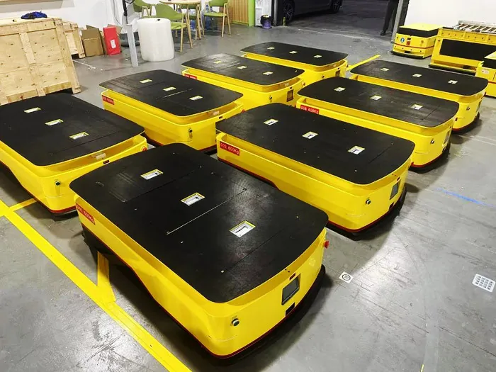 Row of low-profile platform AGVs with flat black decks on a workshop floor