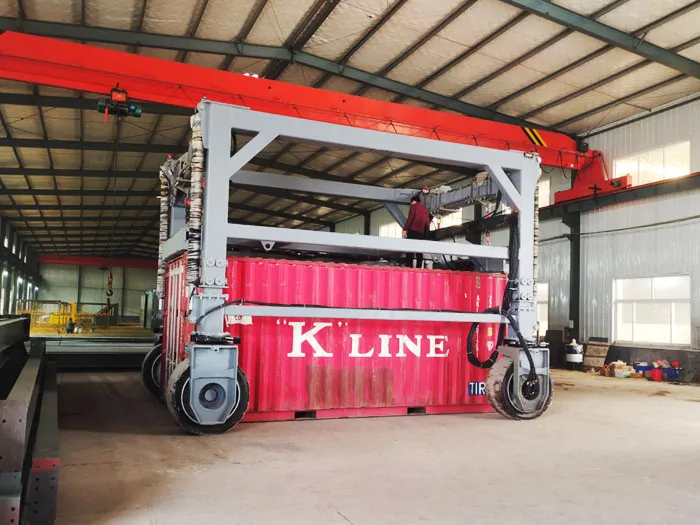 Container straddle carrier astride a shipping container inside a workshop