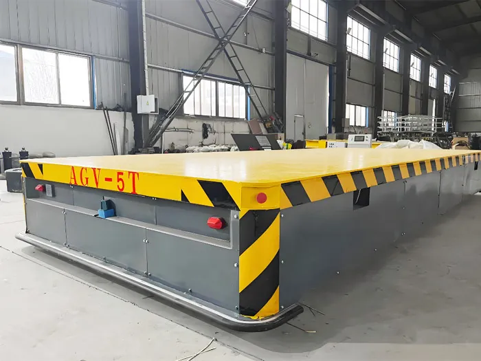 Heavy-duty AGV transfer vehicle with a large flat deck in a steel workshop