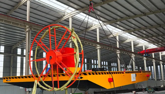Cable reel rail transfer cart lifted by crane, showing the cable reel at the cart end