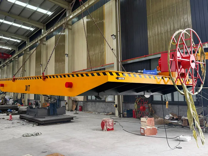 Rail transfer cart with cable reel suspended from an overhead crane in the workshop