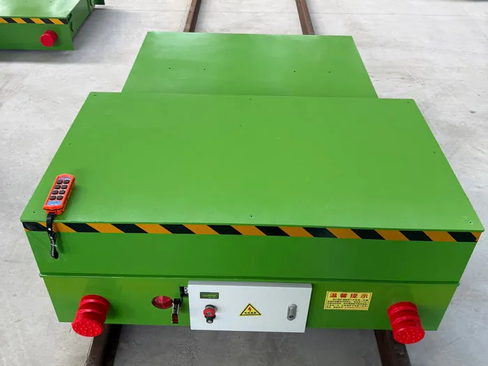 Battery powered rail transfer cart on its track with a wireless remote control on the deck