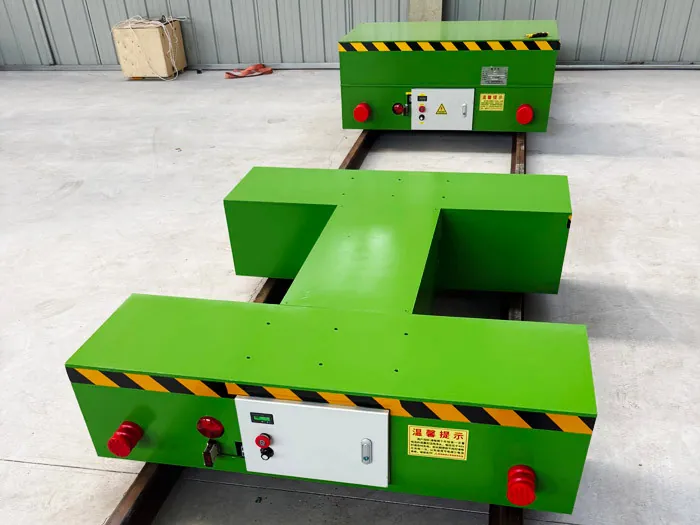 Two battery powered rail transfer carts on embedded rails, one with a custom-shaped deck